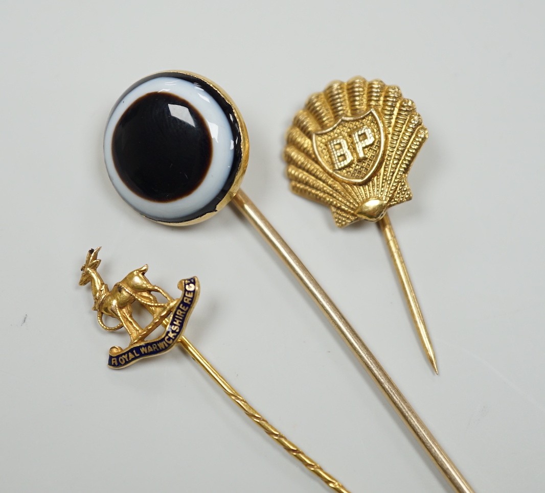 A Victorian yellow metal and banded agate set stick pin, 84mm, a yellow metal Royal Warwickshire Regt. stick pin and a 1970's 9ct gold BP stick pin, gross weight 11.5 grams.